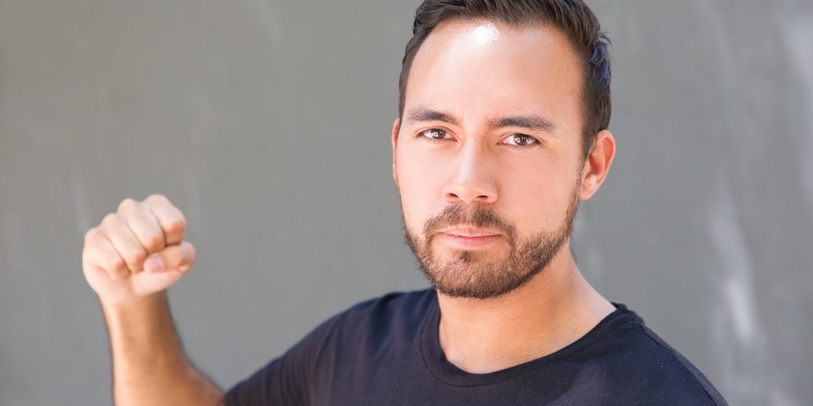 Aggressive Young Man Showing Fist. Serious Bearded Man Looking A