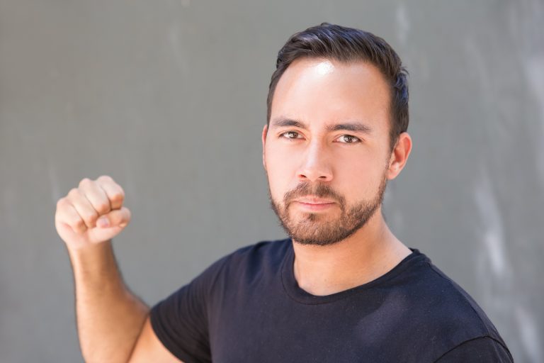 Aggressive Young Man Showing Fist. Serious Bearded Man Looking A