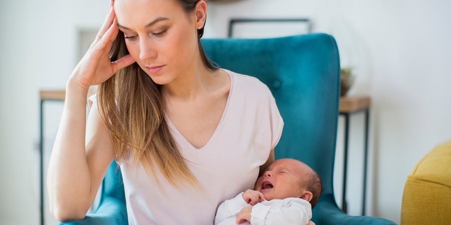 Stressed Mother Holding Crying Baby Suffering From Post Natal De
