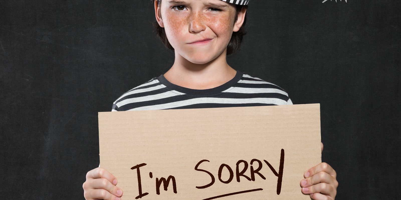 Closeup mugshot photo of boy holding I’m sorry sign. Young boy m