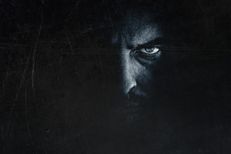 Dark man portrait with scary evil eye. Spooky male face hiding i
